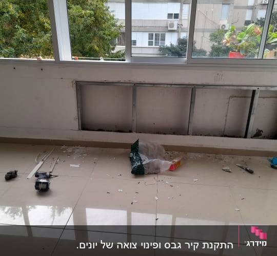 קיר גבס פתוח עם מסגרת מתכת וכלי עבודה על הרצפה